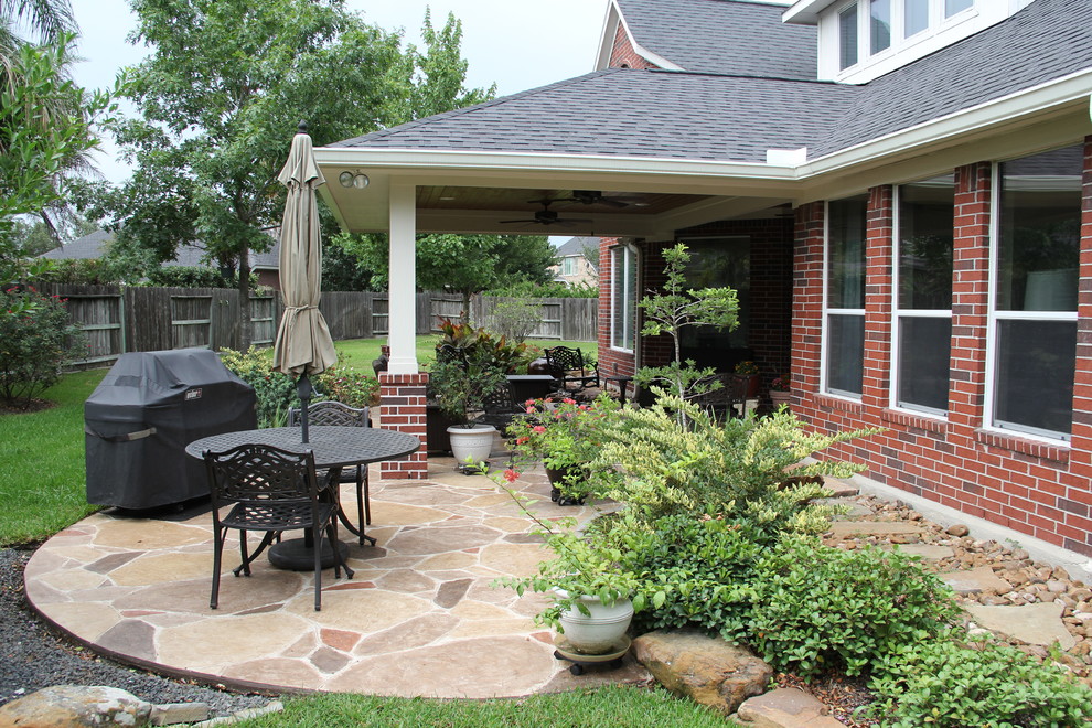Mid-sized elegant backyard stamped concrete patio photo in Houston with a roof extension