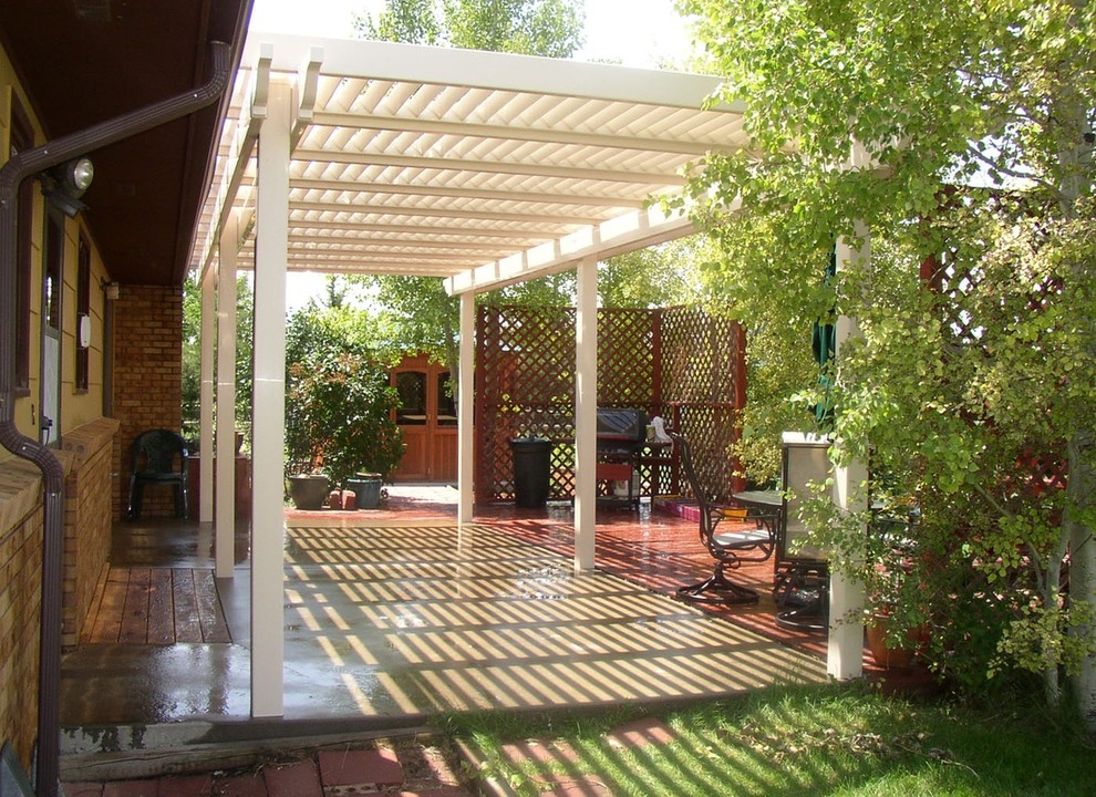 Immagine di un piccolo patio o portico classico dietro casa con lastre di cemento e una pergola