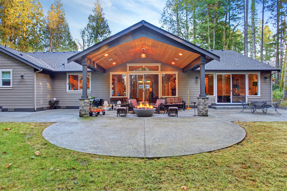 Ispirazione per un grande patio o portico stile americano dietro casa con un focolare, lastre di cemento e un tetto a sbalzo
