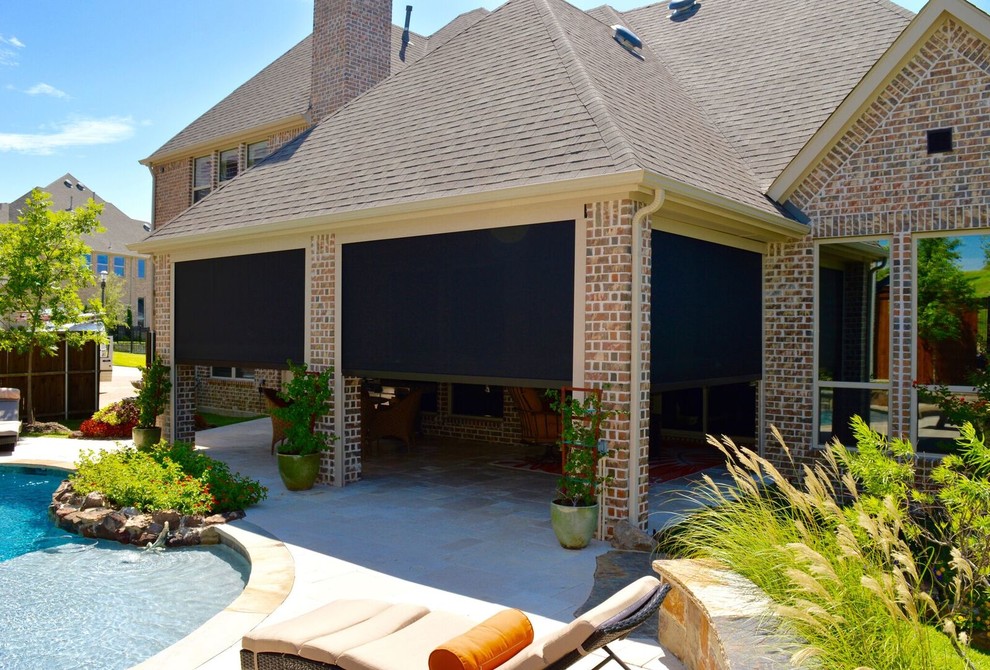 This is an example of a medium sized traditional back patio in Dallas with an outdoor kitchen, natural stone paving and a roof extension.