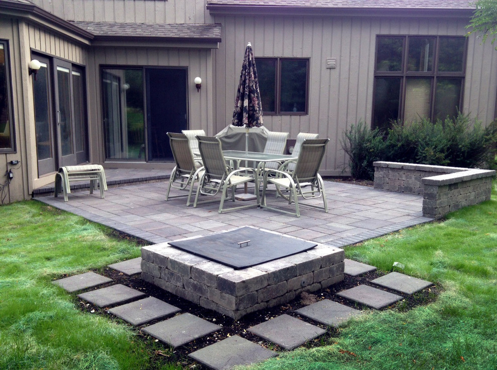 Imagen de patio clásico de tamaño medio sin cubierta en patio trasero con brasero y adoquines de ladrillo
