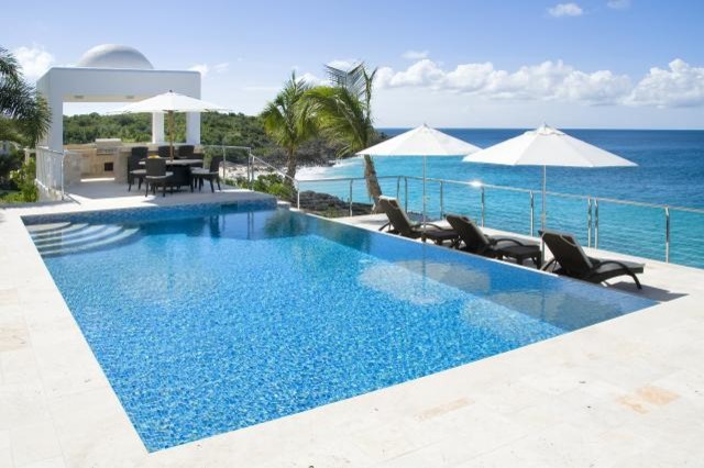 Idee per un'ampia piscina costiera dietro casa con pavimentazioni in pietra naturale