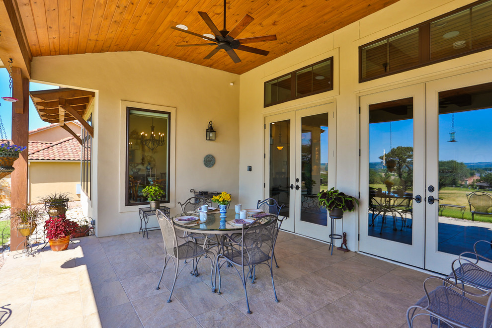 Photo of a large classic back patio in Austin with an outdoor kitchen, tiled flooring and a roof extension.