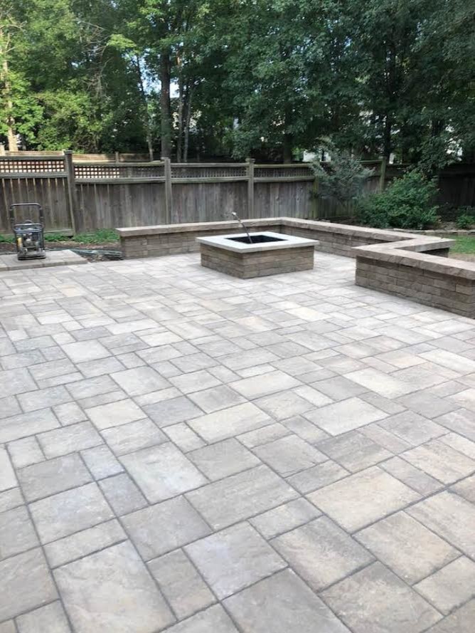 Example of a large transitional backyard stamped concrete patio design in Raleigh with a fire pit and no cover
