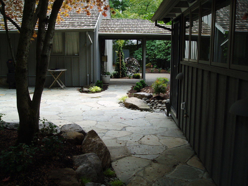 Large world-inspired back patio in Portland with natural stone paving and a roof extension.
