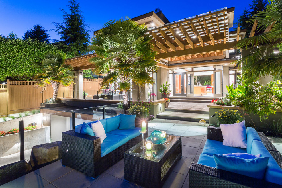 Large contemporary back patio in Vancouver with a pergola and concrete paving.