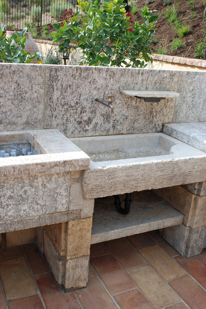 This is an example of a large mediterranean back patio in New York with an outdoor kitchen and natural stone paving.