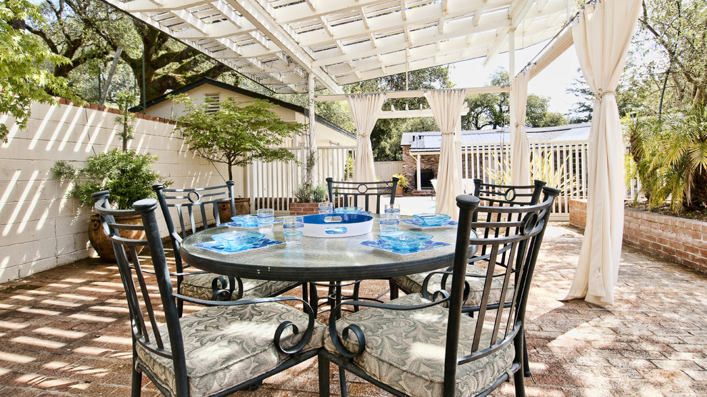 Ejemplo de patio tradicional renovado de tamaño medio en patio trasero con jardín de macetas, adoquines de ladrillo y pérgola