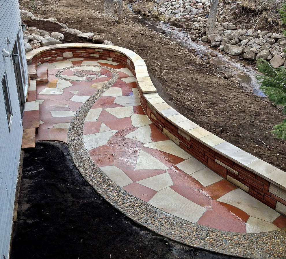 Inspiration for a large eclectic back patio in Denver with natural stone paving and no cover.