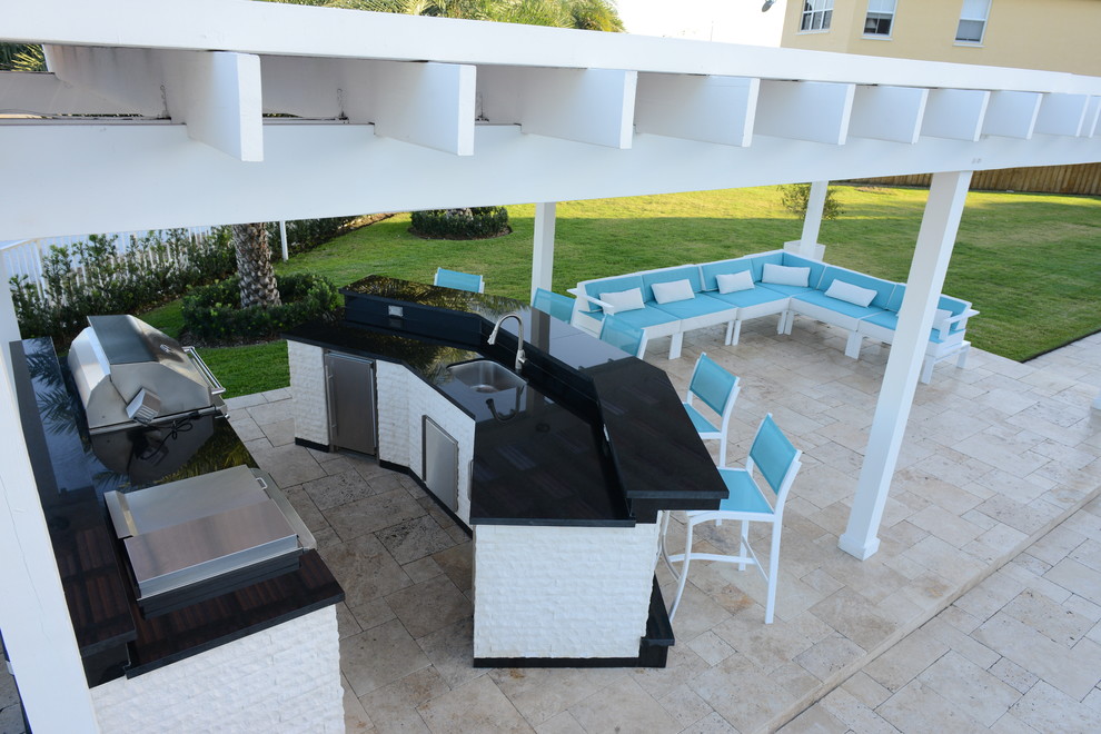 Geräumige Pergola hinter dem Haus mit Outdoor-Küche und Natursteinplatten in Miami