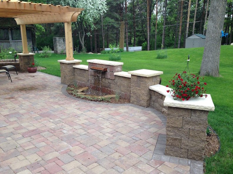 This is an example of a medium sized classic back patio in Minneapolis with a water feature, concrete paving and a pergola.
