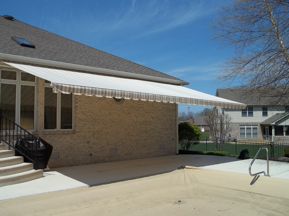 Esempio di un patio o portico classico di medie dimensioni e dietro casa con lastre di cemento e un parasole