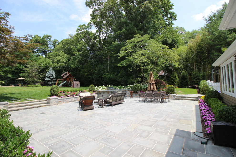 Modelo de patio clásico extra grande sin cubierta en patio trasero con cocina exterior y adoquines de piedra natural