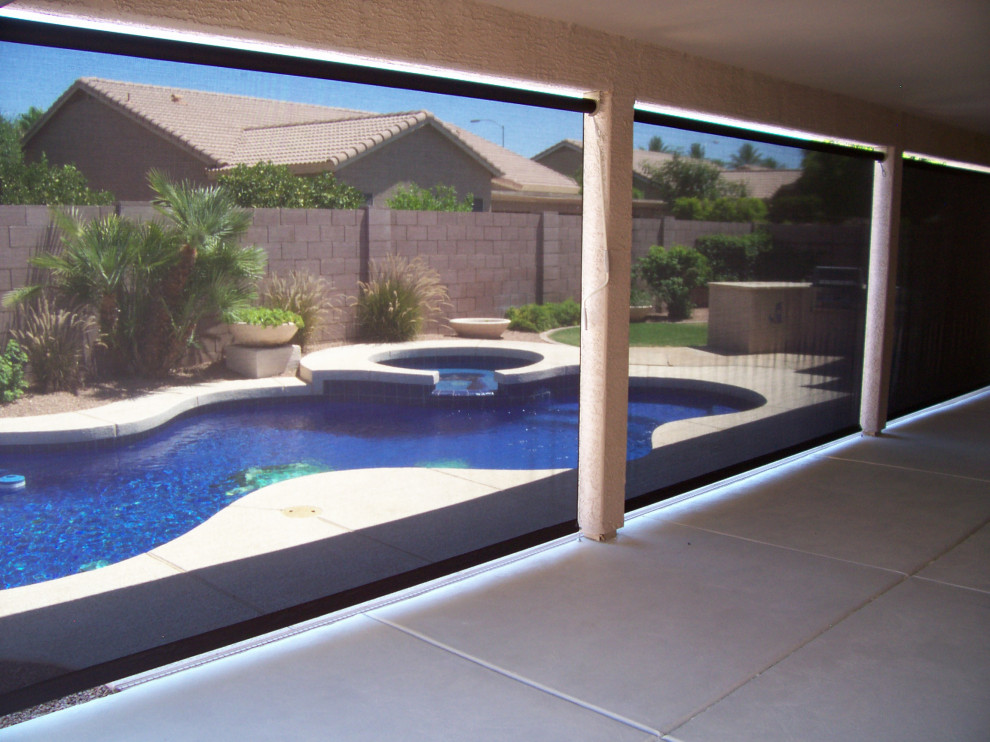 Cette image montre une grande terrasse arrière design avec une dalle de béton et un auvent.