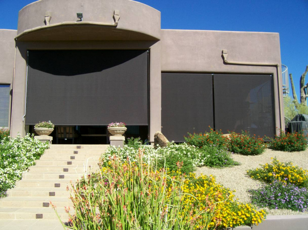 Exempel på en stor modern uteplats på baksidan av huset, med betongplatta och markiser