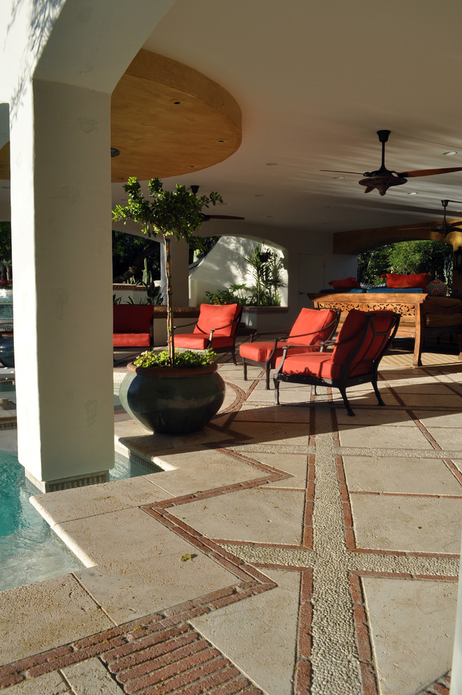 Esempio di un ampio patio o portico mediterraneo dietro casa con piastrelle