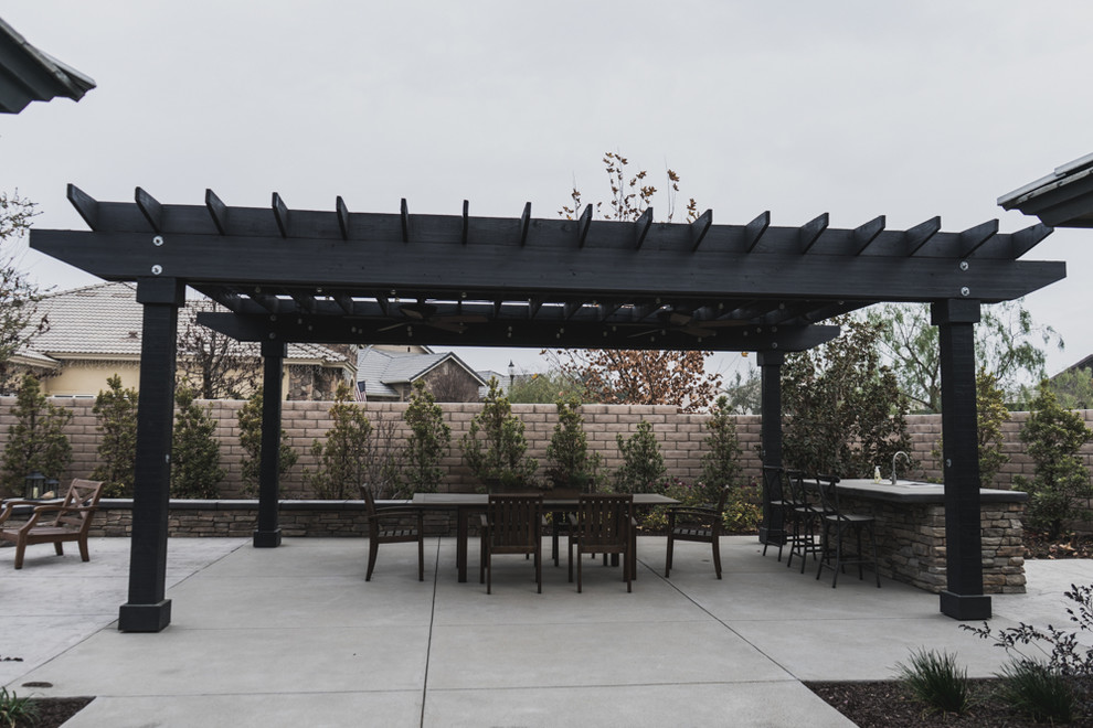 Foto di un grande patio o portico tradizionale dietro casa con lastre di cemento e una pergola