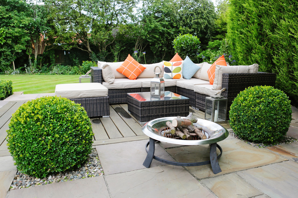 Photo of a medium sized contemporary back patio in Cheshire with a fire feature, natural stone paving and a pergola.