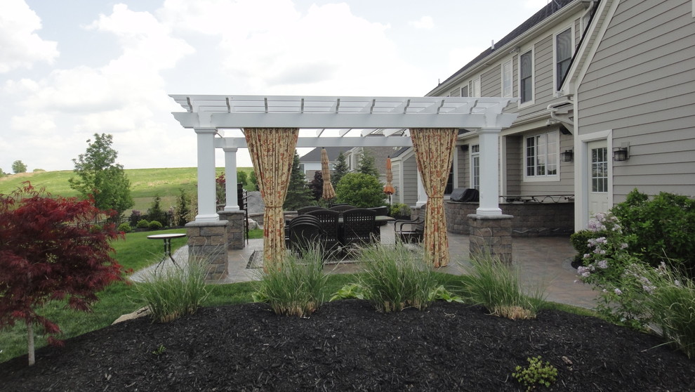 Example of a large classic backyard concrete paver patio design in New York with a pergola