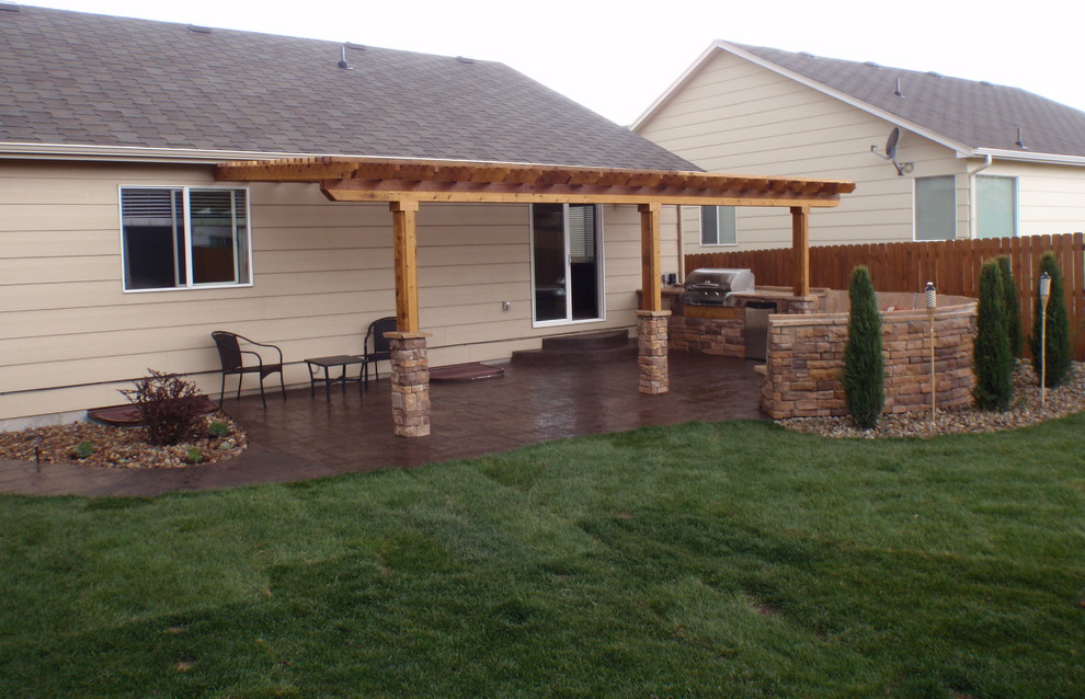 Modelo de patio clásico de tamaño medio en patio trasero con cocina exterior, suelo de hormigón estampado y pérgola
