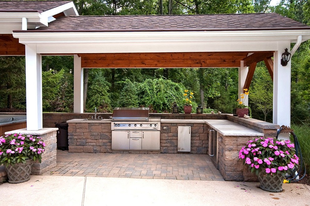 Ejemplo de patio clásico grande en patio trasero con cocina exterior, adoquines de ladrillo y cenador