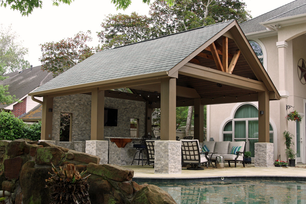 Ispirazione per un grande patio o portico chic dietro casa con pavimentazioni in pietra naturale e un tetto a sbalzo