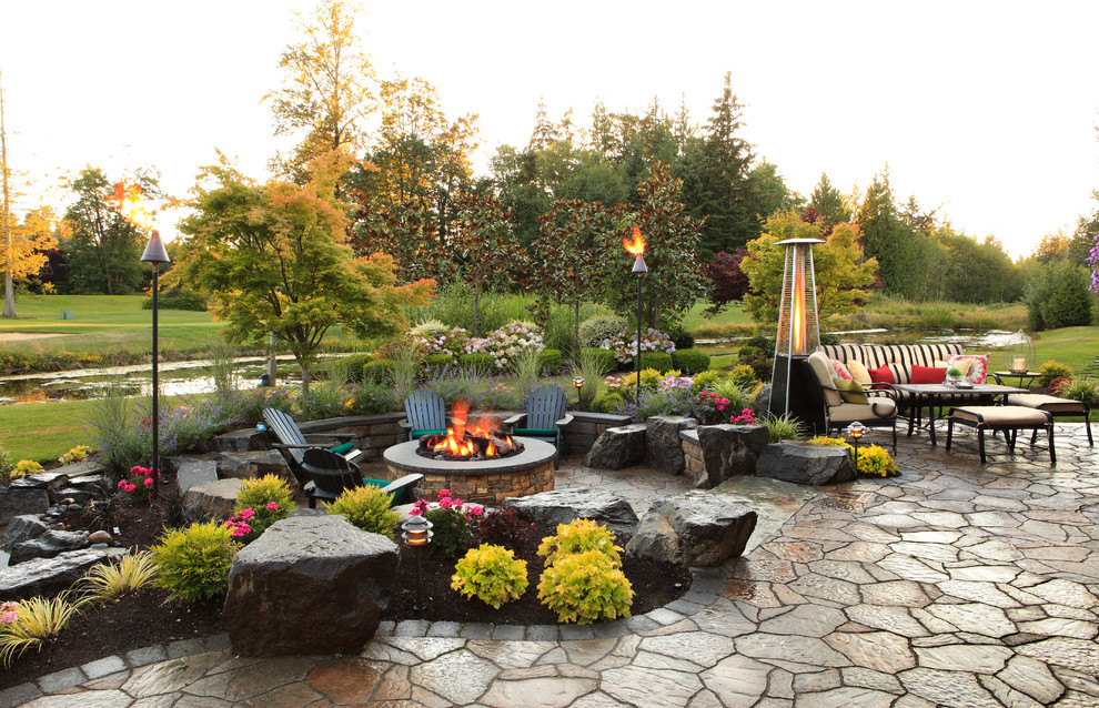 Example of a classic stone patio design in Seattle with a fire pit and no cover