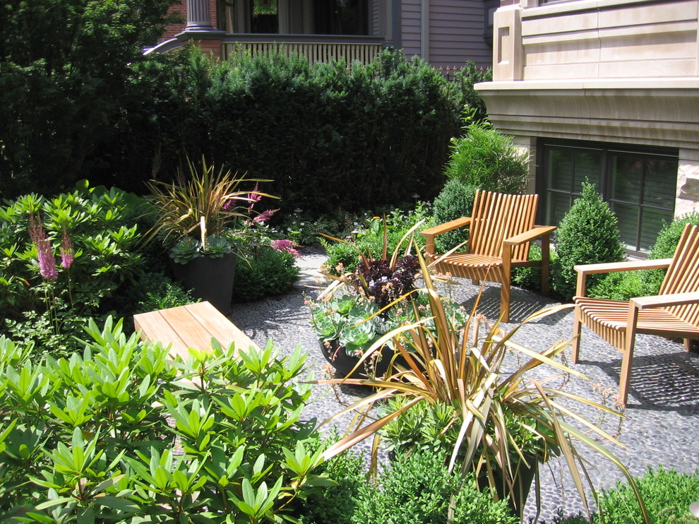 Ejemplo de patio actual sin cubierta en patio trasero con jardín de macetas y adoquines de piedra natural