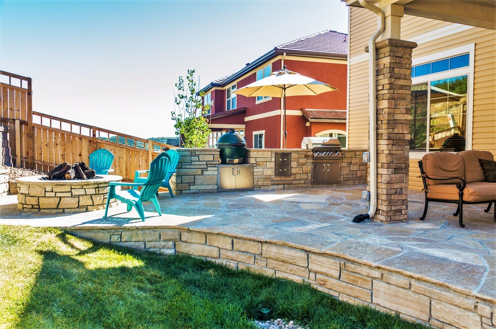 Exemple d'une terrasse arrière tendance de taille moyenne avec une cuisine d'été et des pavés en pierre naturelle.