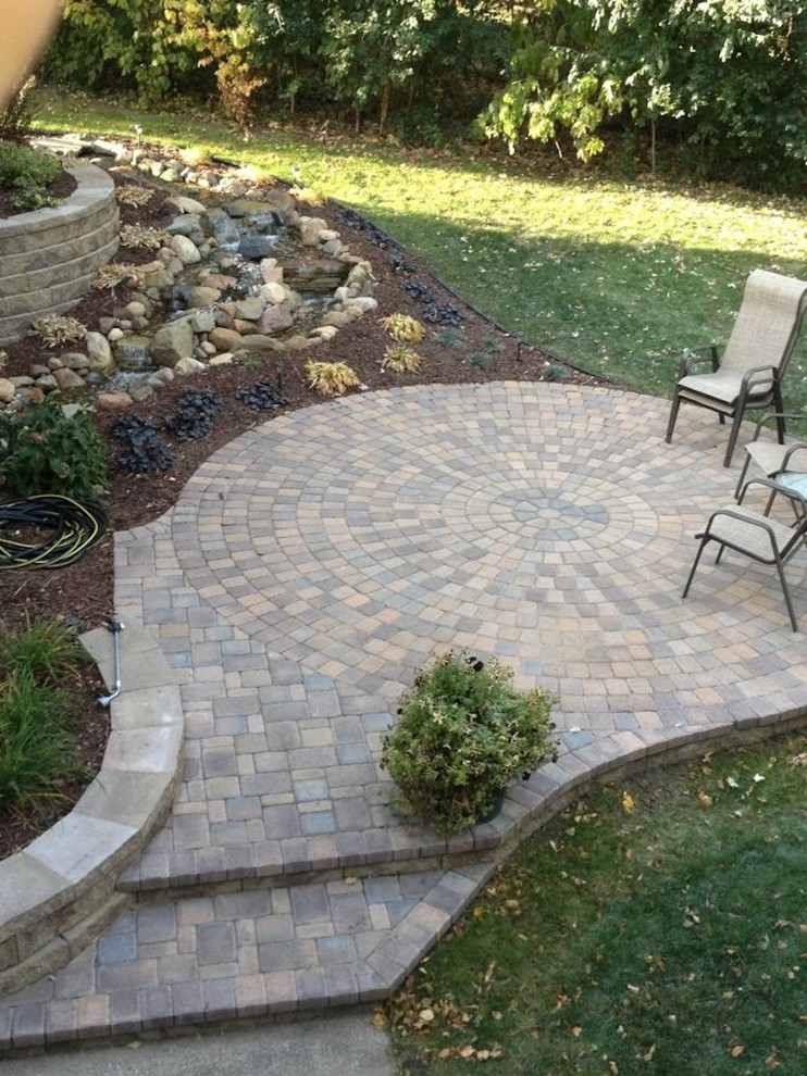 Medium sized classic back patio in Minneapolis with a water feature and brick paving.