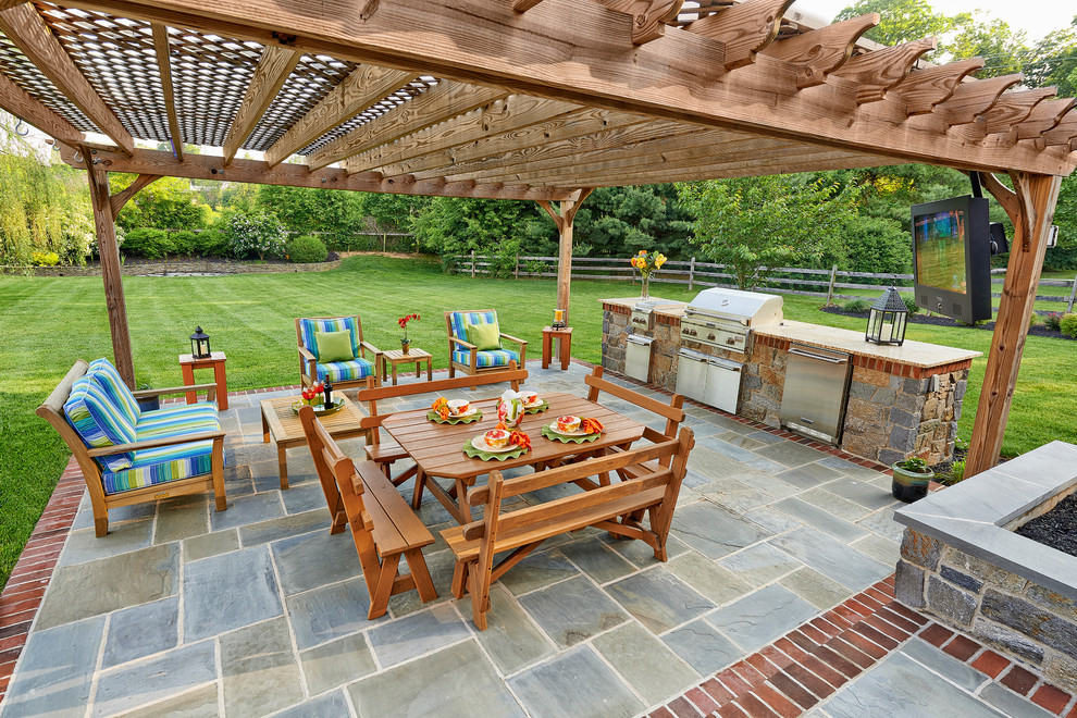 Aménagement d'une terrasse classique avec une cuisine d'été, des pavés en pierre naturelle et une pergola.