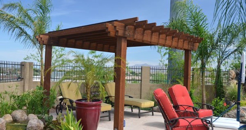 Patio kitchen - large tropical backyard stone patio kitchen idea in Phoenix with a pergola