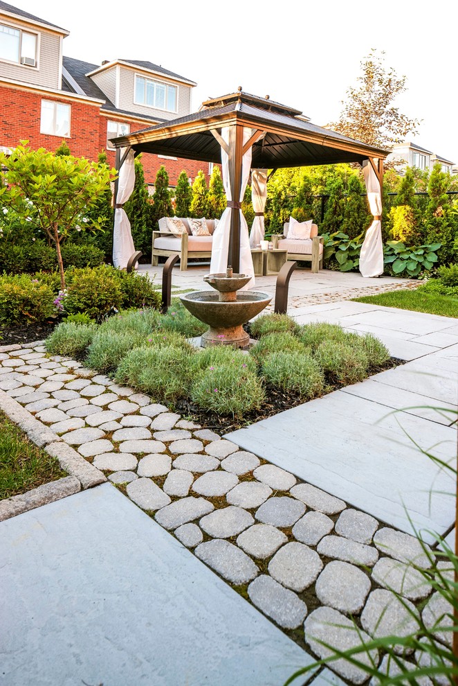 Diseño de patio clásico renovado grande en patio trasero con fuente, losas de hormigón y cenador