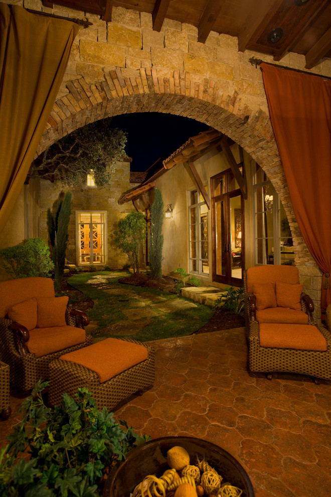 Immagine di un patio o portico mediterraneo dietro casa con un parasole e piastrelle