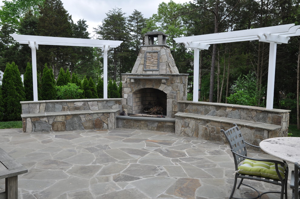 Immagine di un grande patio o portico classico dietro casa con un focolare, pavimentazioni in pietra naturale e una pergola