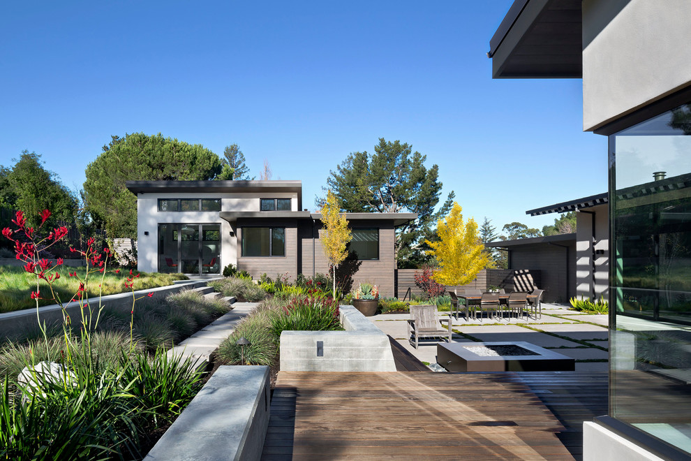 This is an example of an expansive contemporary back patio in San Francisco with a fire feature, concrete slabs and no cover.