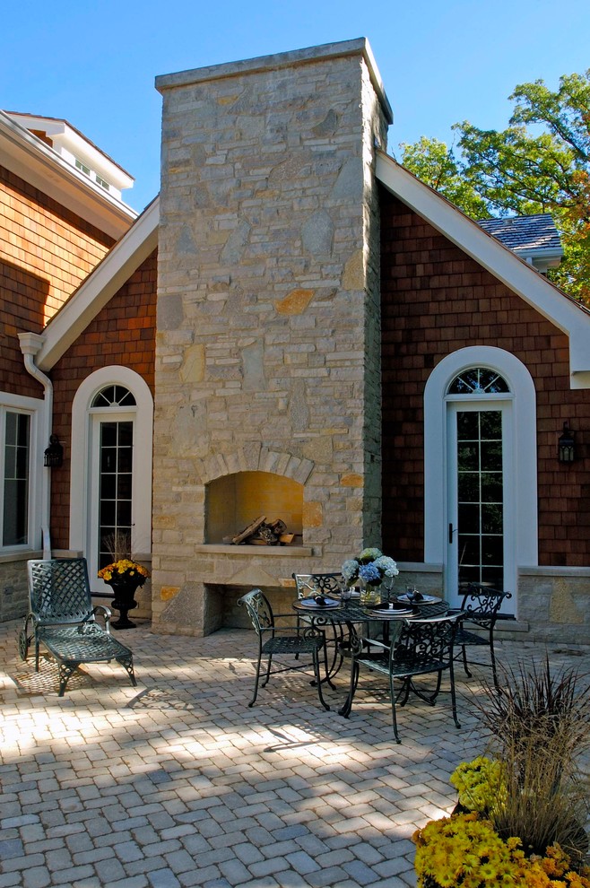 Idee per un ampio patio o portico classico dietro casa con pavimentazioni in mattoni, un focolare e nessuna copertura