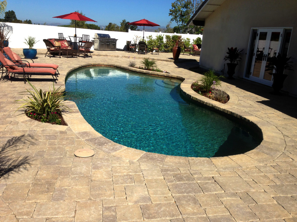 Inspiration pour une grande piscine arrière traditionnelle avec des pavés en pierre naturelle.