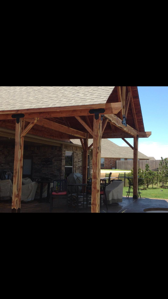 Large rustic back patio in Oklahoma City with concrete slabs and a roof extension.