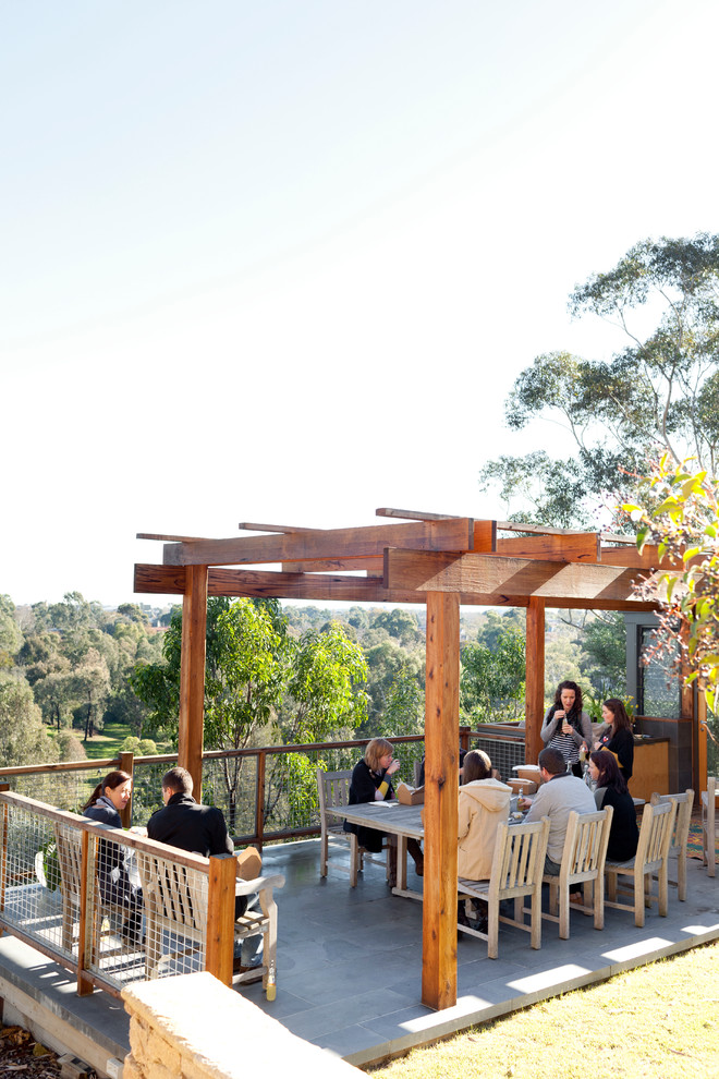 Idée de décoration pour une terrasse design avec des pavés en pierre naturelle et un gazebo ou pavillon.