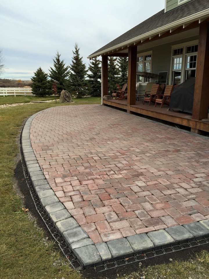 This is an example of a large rustic back patio in Calgary with brick paving.
