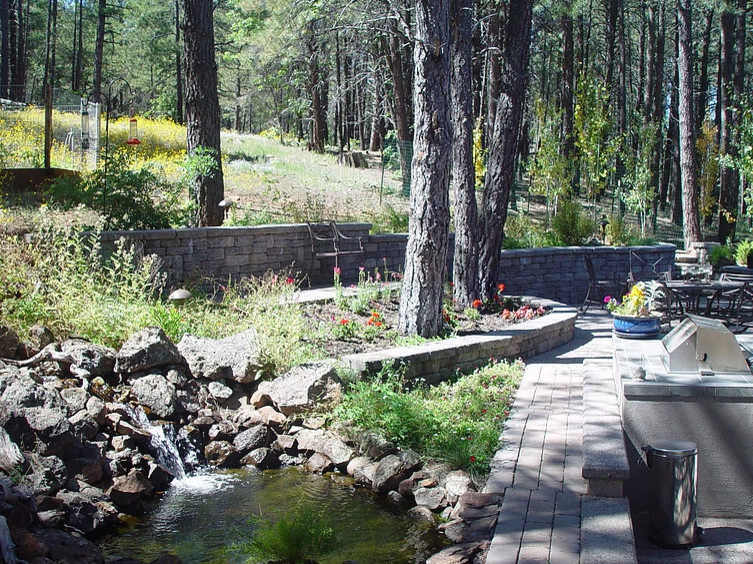 Cette photo montre une terrasse arrière chic de taille moyenne avec un point d'eau, des pavés en pierre naturelle et un auvent.