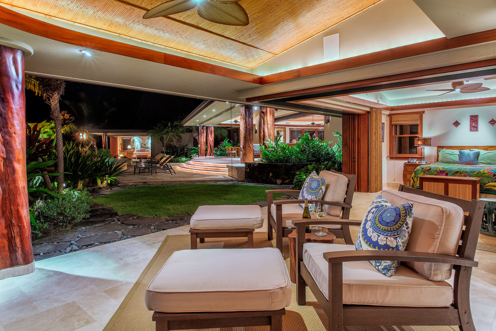 Example of an island style backyard tile patio fountain design in Hawaii with a roof extension