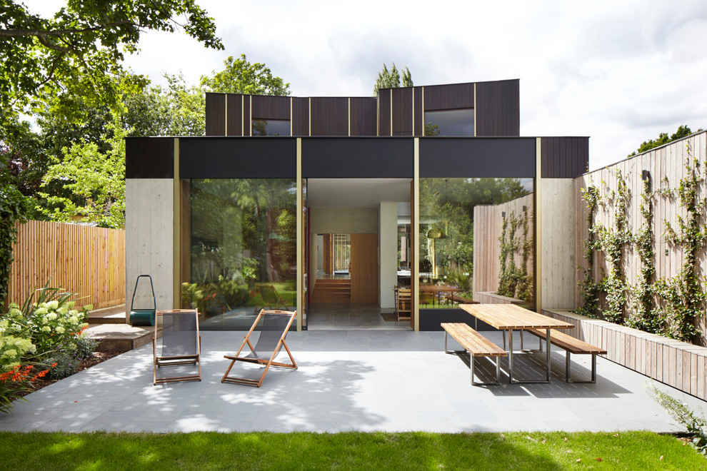 Cette image montre une grande terrasse arrière minimaliste avec des pavés en pierre naturelle.
