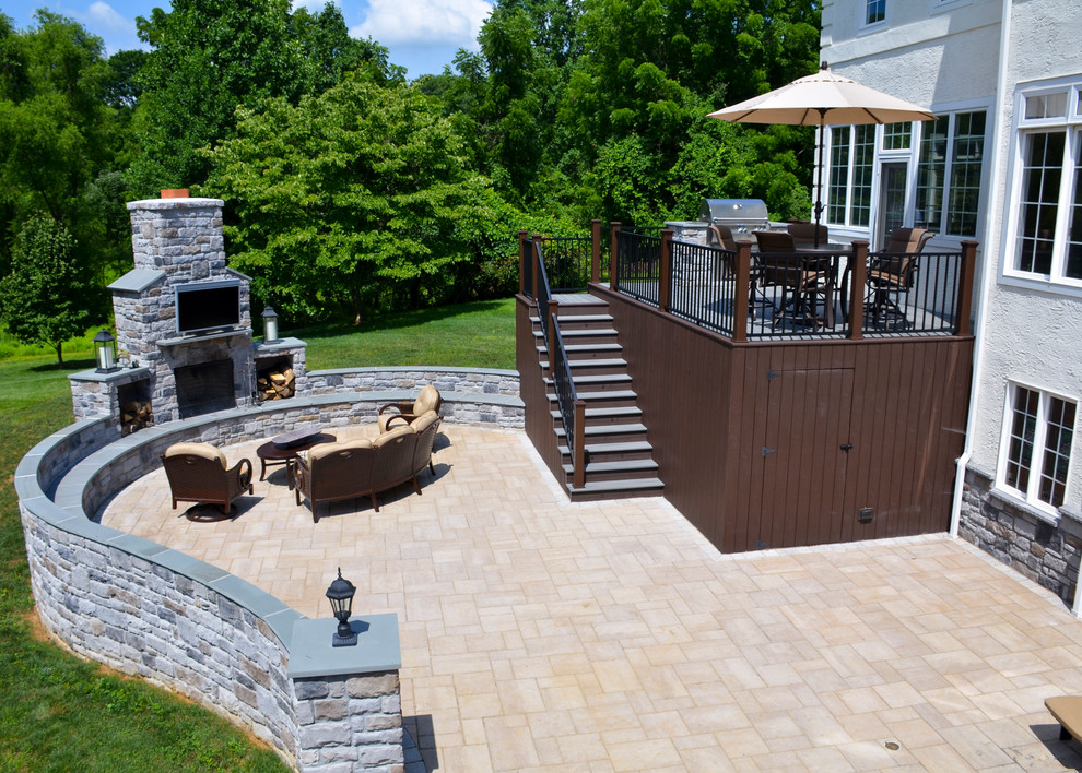 This is an example of an expansive traditional back patio in Philadelphia with a fire feature, concrete paving and a roof extension.