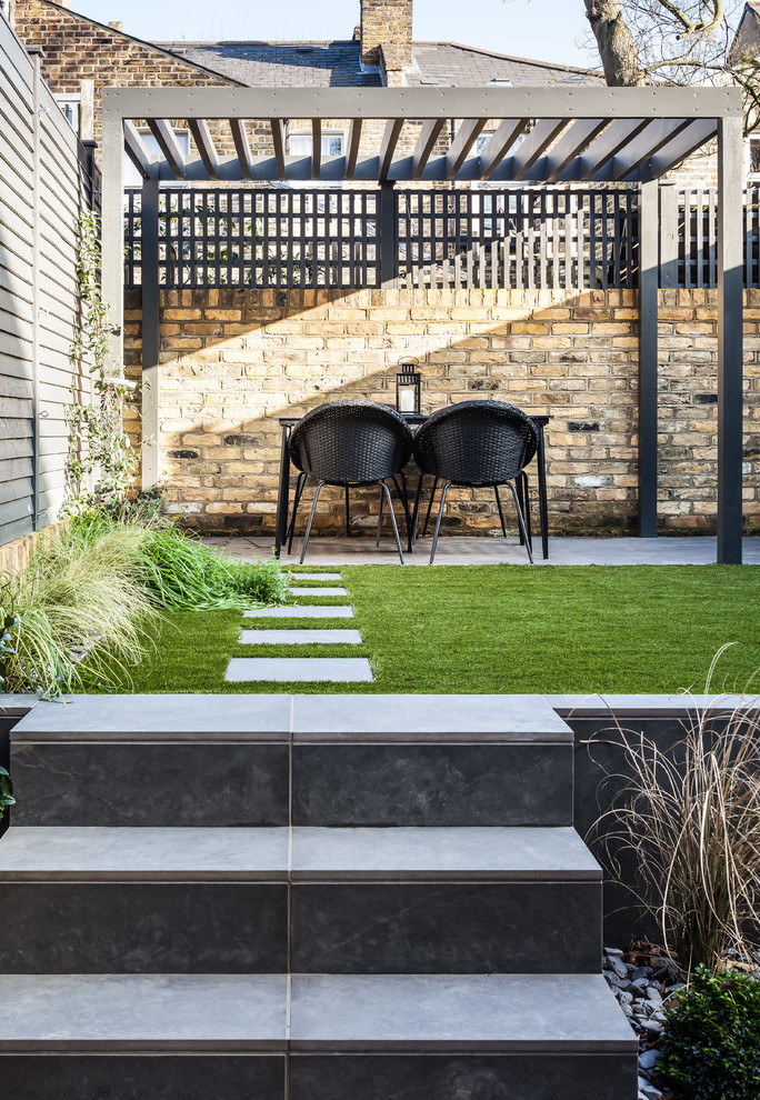 Diseño de patio contemporáneo de tamaño medio en patio trasero con adoquines de piedra natural y pérgola