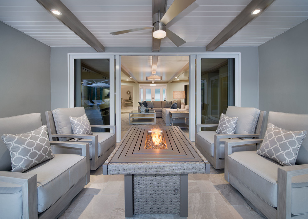 Large contemporary back patio in Miami with a fire feature, tiled flooring and a roof extension.