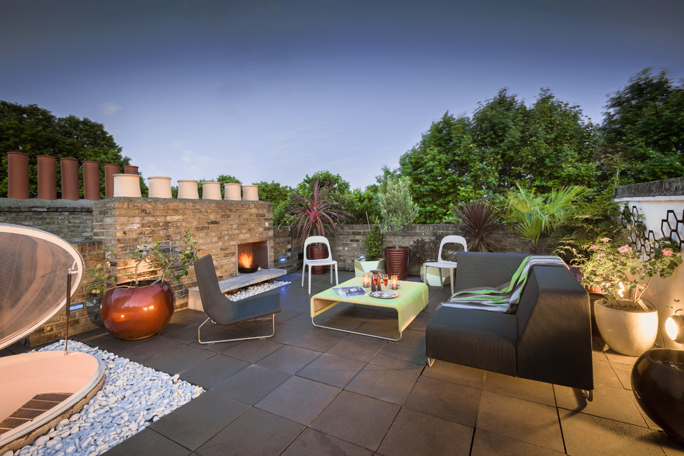Photo of a medium sized contemporary patio in London with a potted garden, no cover and tiled flooring.