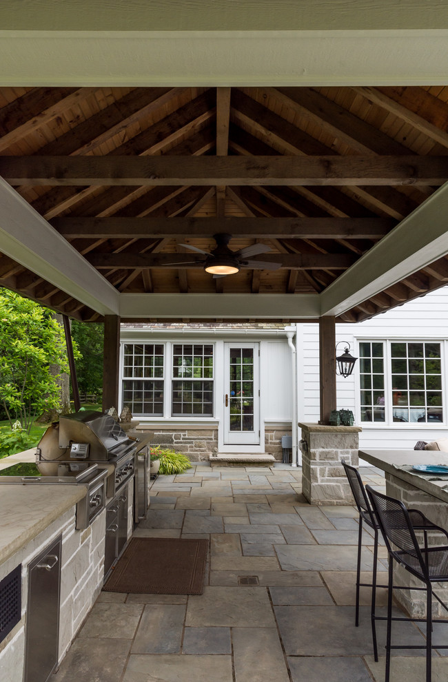 Modelo de patio tradicional de tamaño medio en patio trasero con cocina exterior, adoquines de piedra natural y cenador