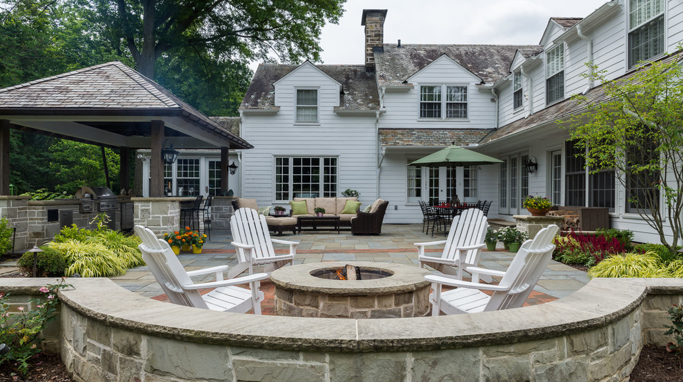 Foto de patio clásico de tamaño medio en patio trasero con cocina exterior, adoquines de piedra natural y cenador